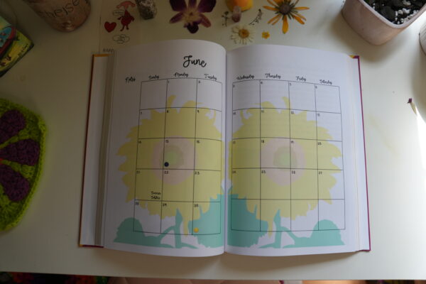 Monthly planner layout with moon phase tracking and a sunflower accent in the background.